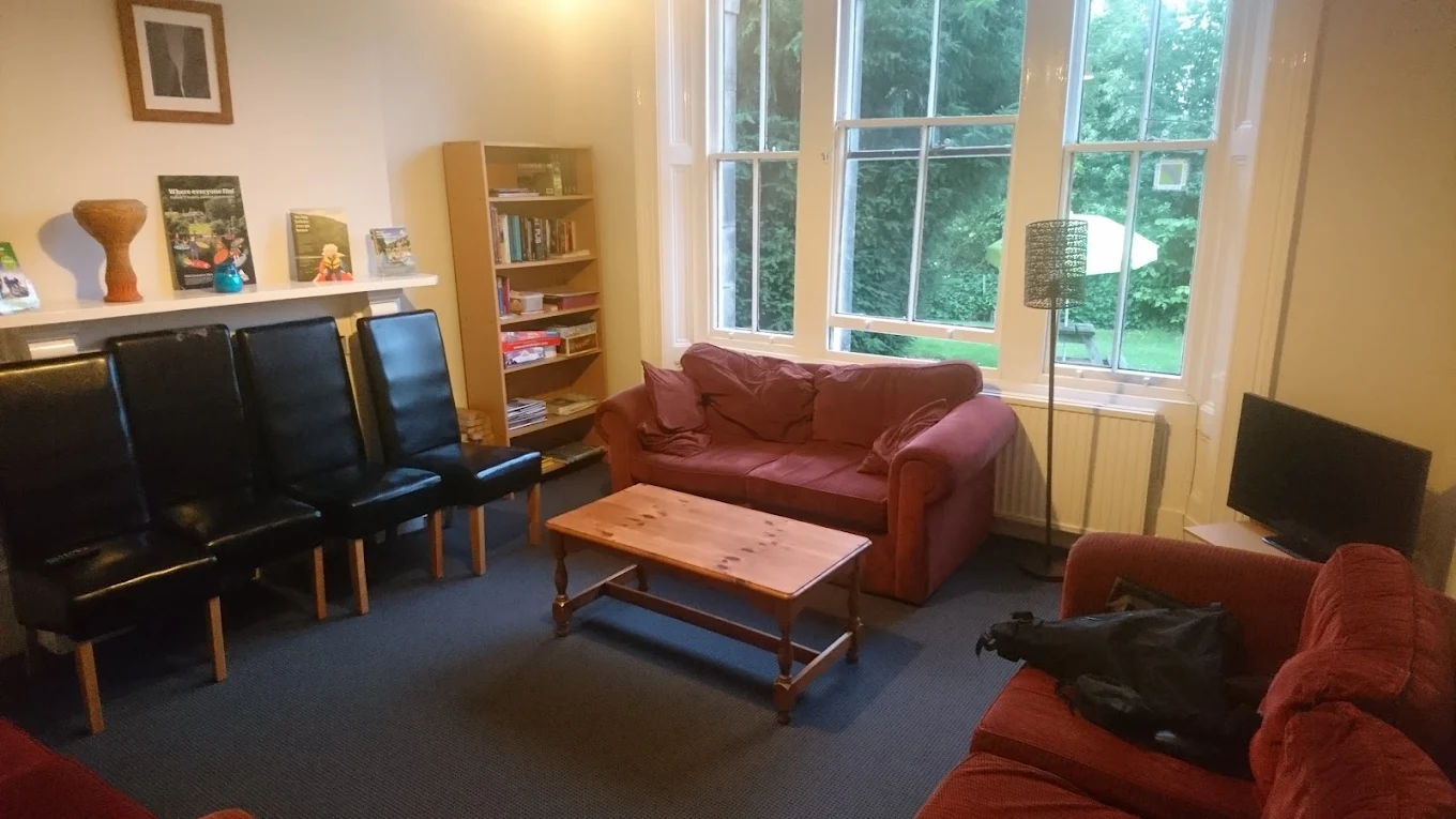 The lounge of the old YHA Hathersage, mismatched chairs and worn carpet