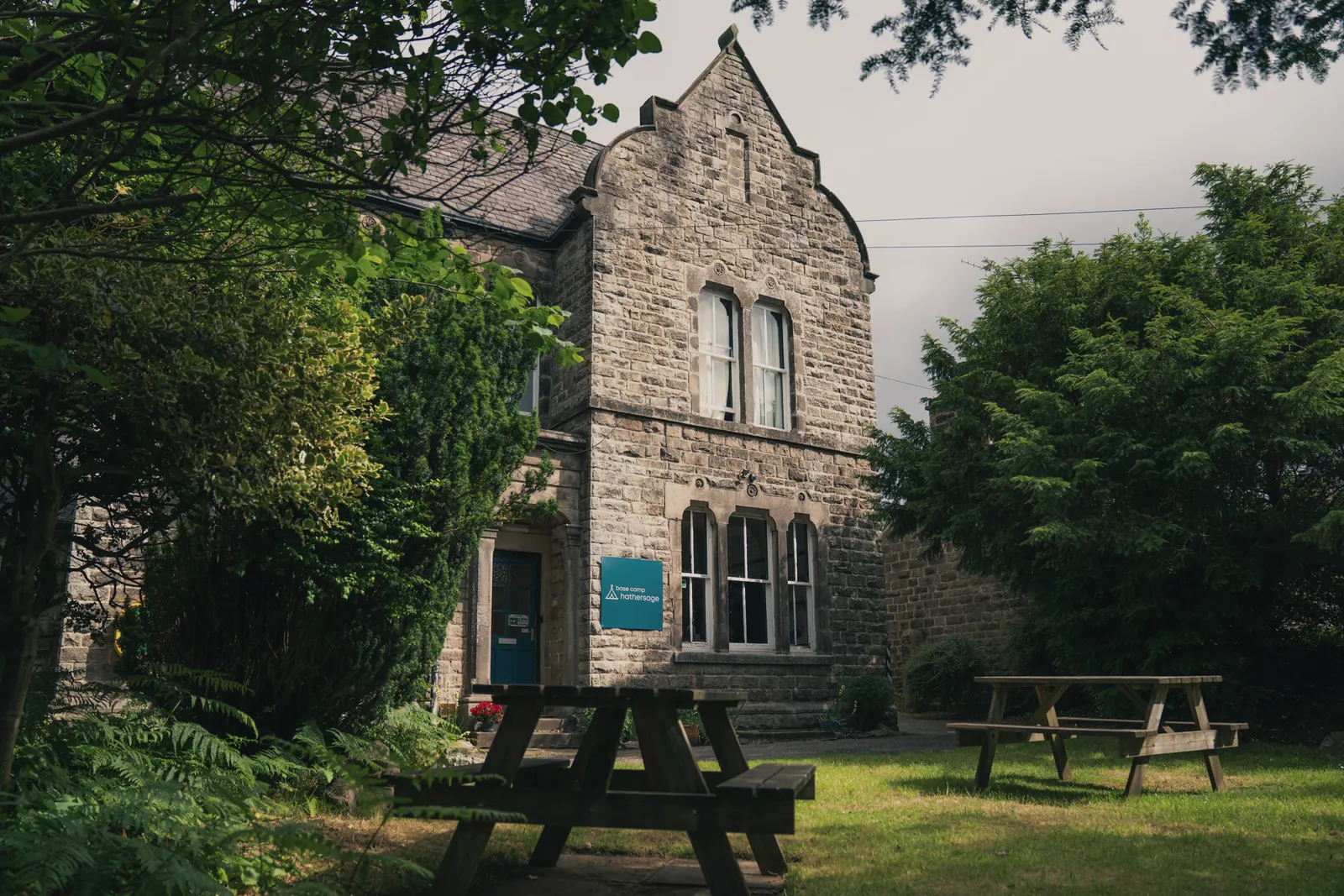 The stone front of Base Camp Hathersage with a picnic bench on the lawn