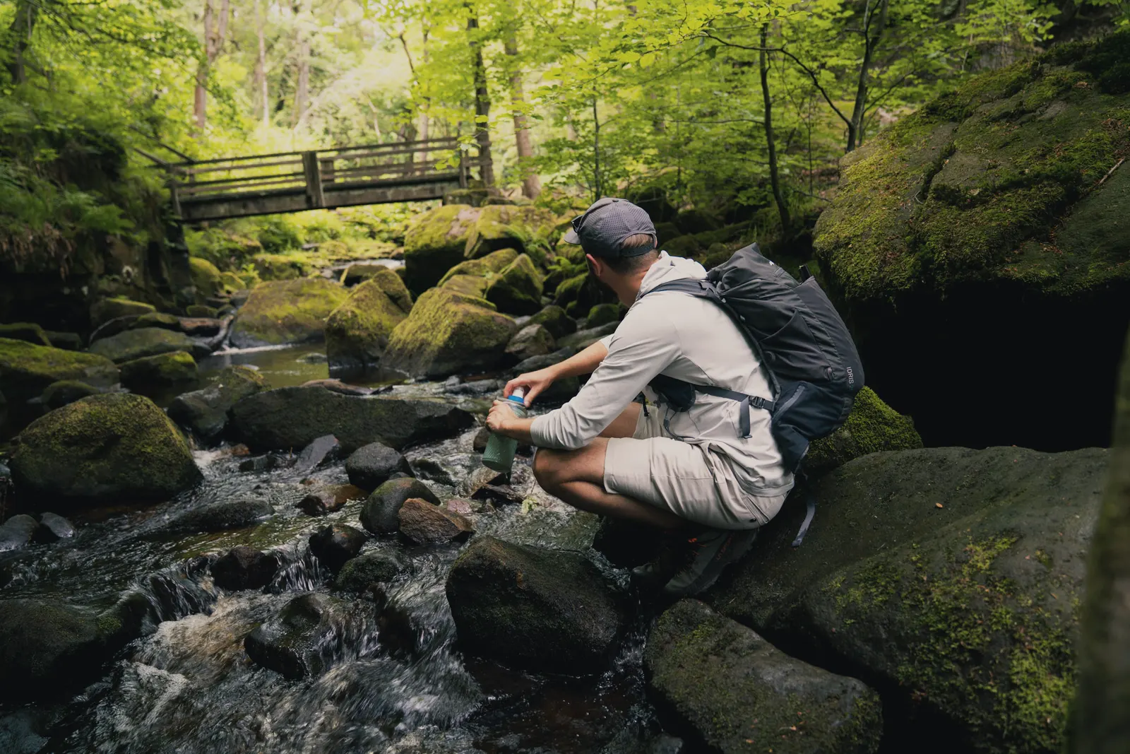 Two walkers taking a break on the rocks beside a stream in Padley Gorge