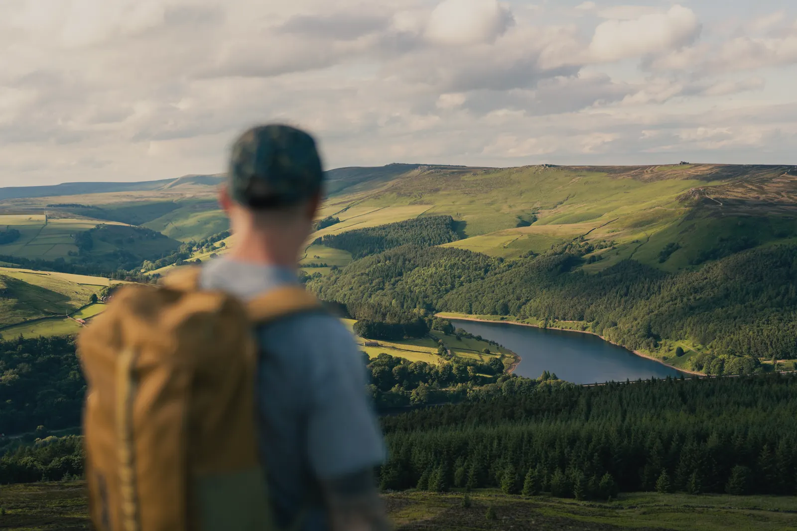 A walker looking out over Ladybower Reservoir from the pine woods above the Hope Valley